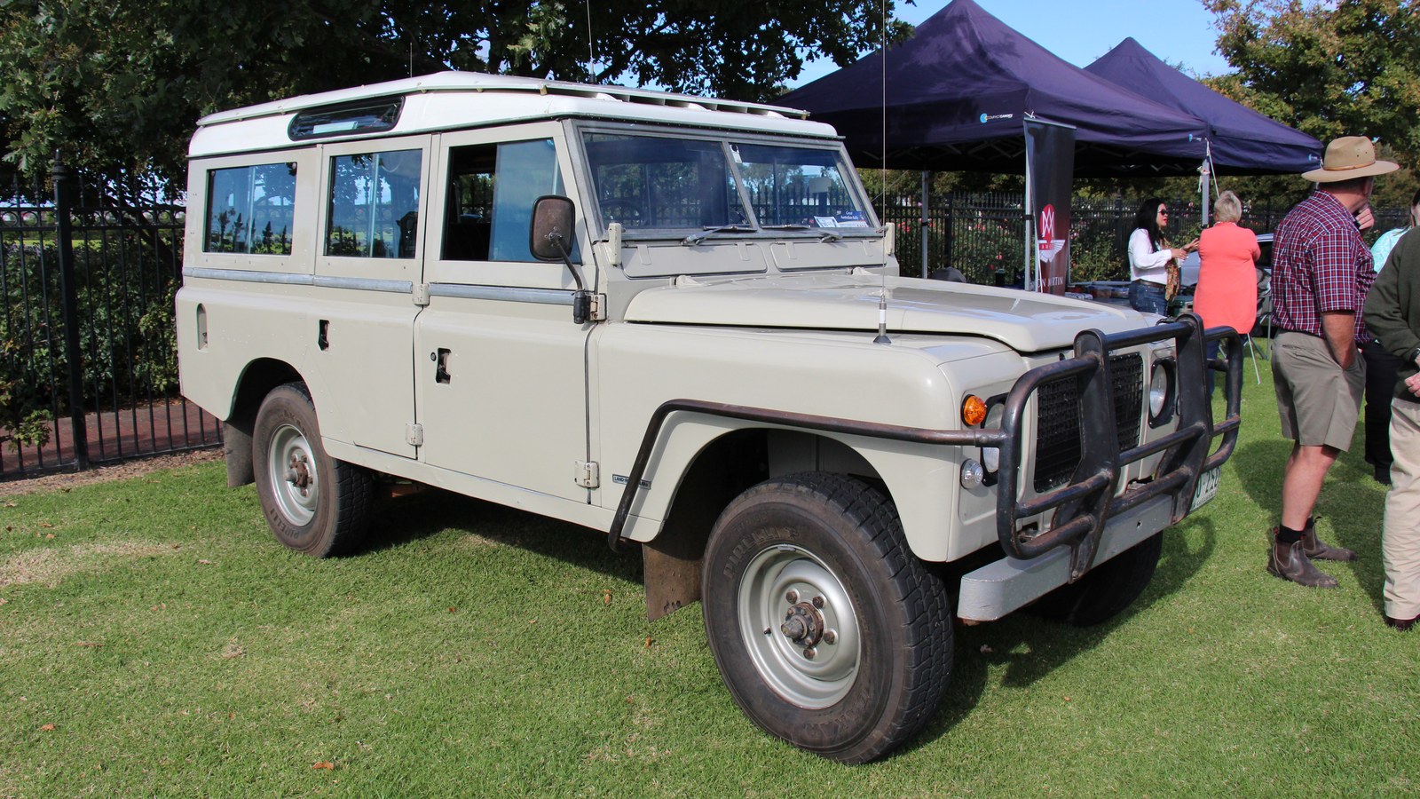 A rugged portable 12V camp shower system hanging from a 4x4 vehicle in the Australian outback.