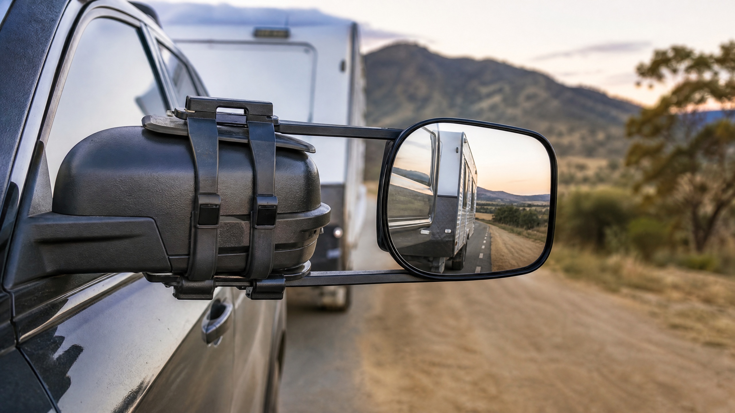 Clip-on towing mirror on a 4x4 vehicle with caravan visible behind