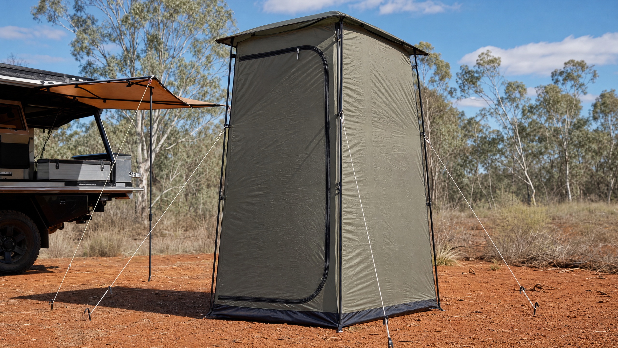 A tall privacy and ensuite tent set up beside a 4x4 vehicle at a bush campsite.