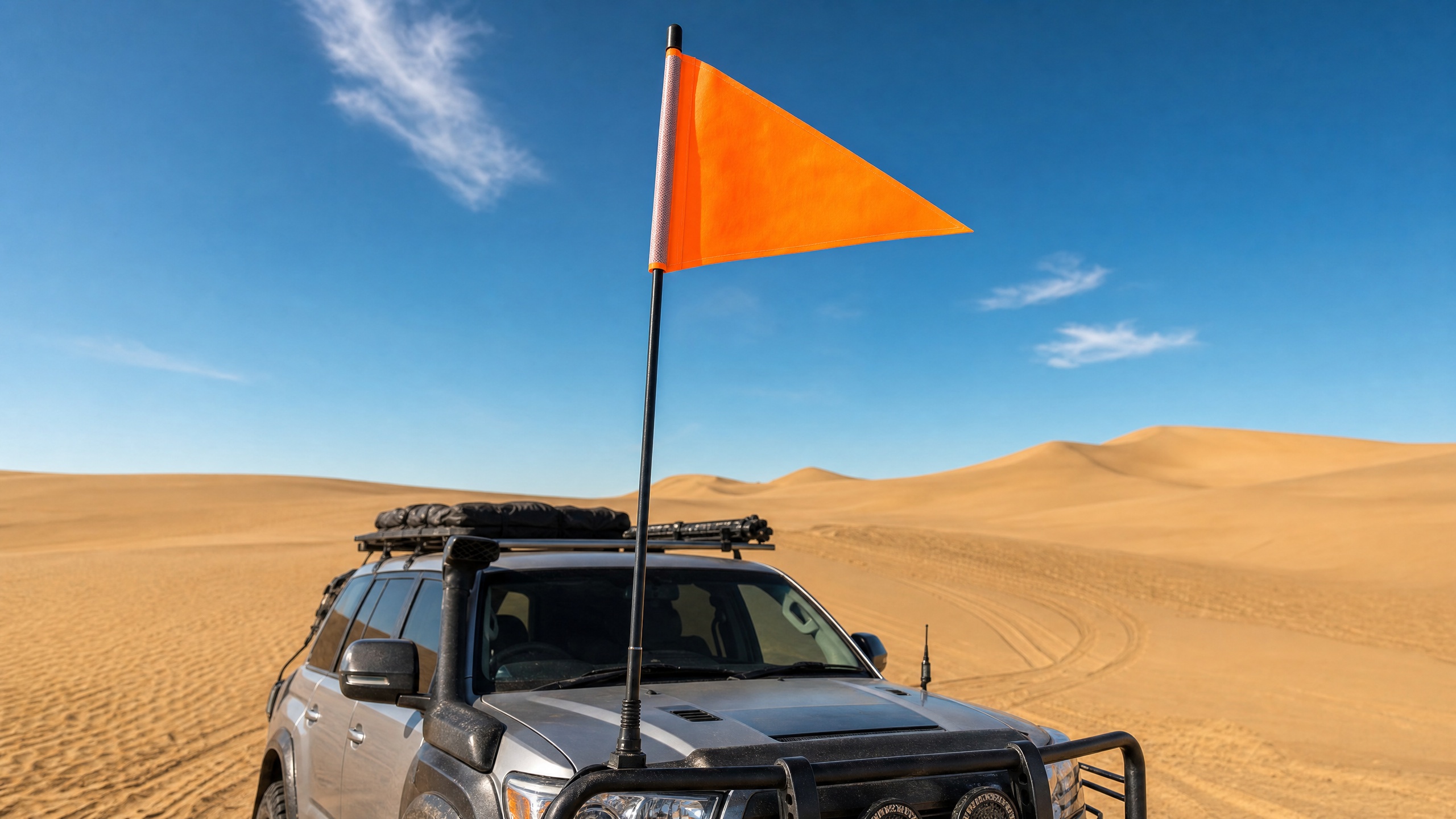 Large bright orange sand flag on a 4x4 vehicle driving in sand dunes