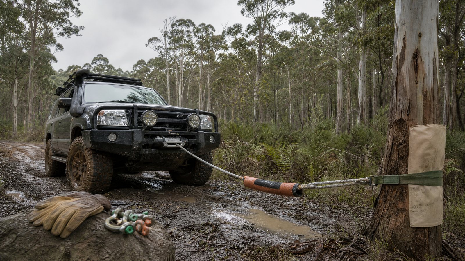 4x4 winch recovery setup with synthetic rope,tree strap and damper on a muddy track