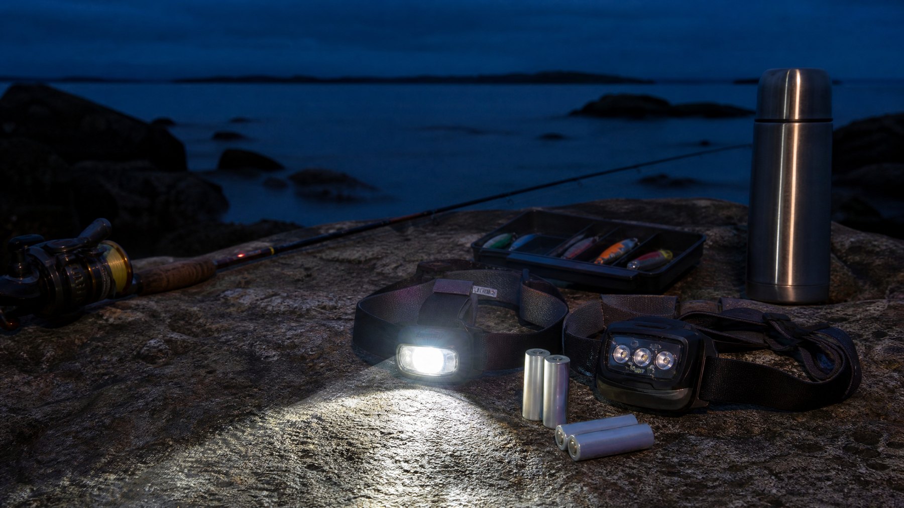 Fishing headlamps illuminating night angling gear on a rocky shore