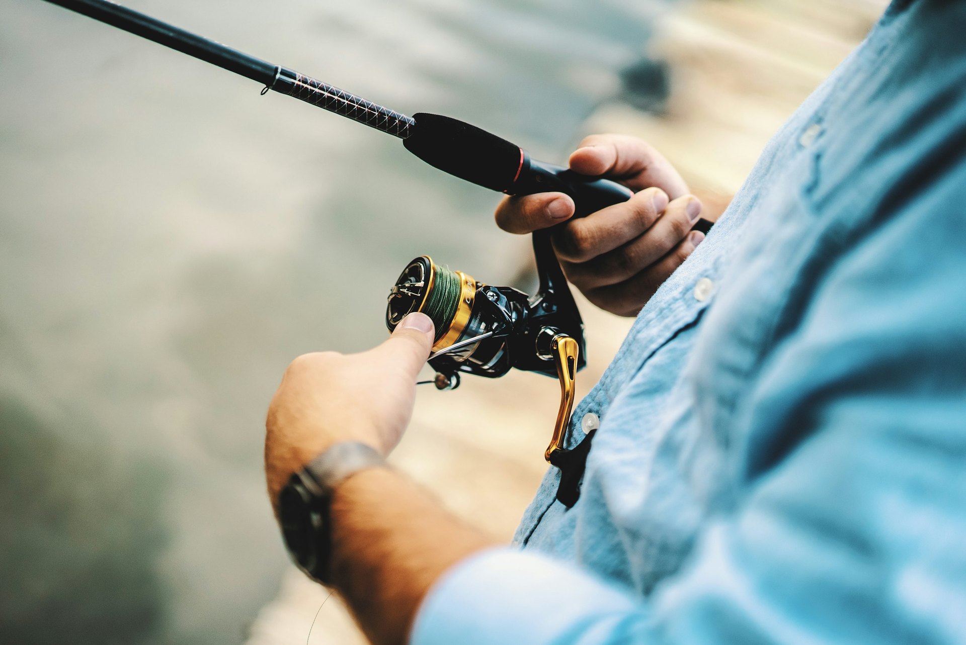 Angler holding a spinning reel on a fishing rod.