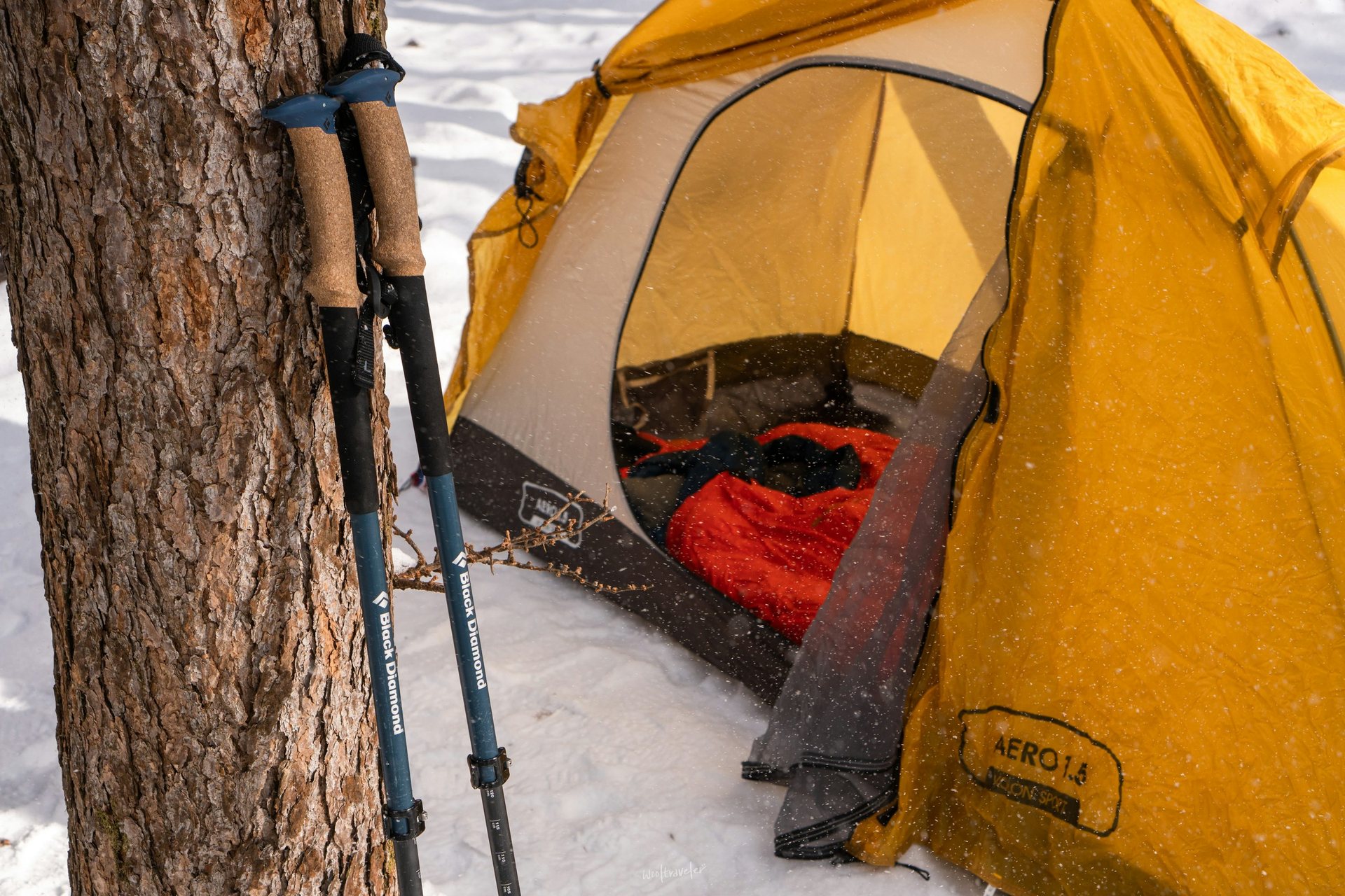 Sleeping bag laid out inside a yellow tent at a snowy campsite