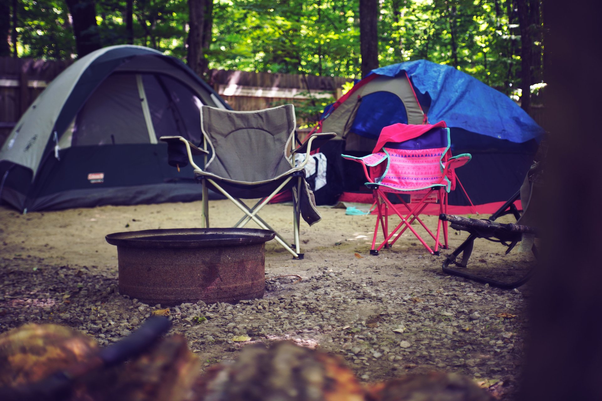 Two camping chairs set up beside tents at a campsite