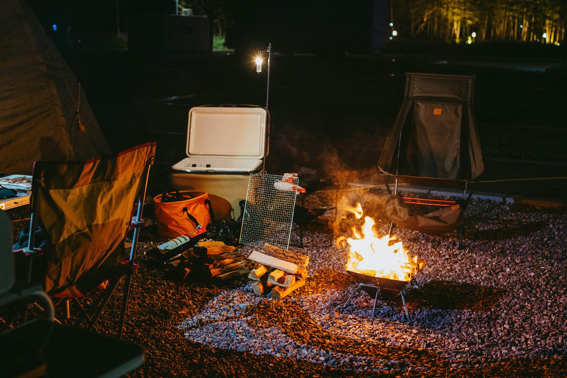 Cooler beside a campfire at a campsite at night