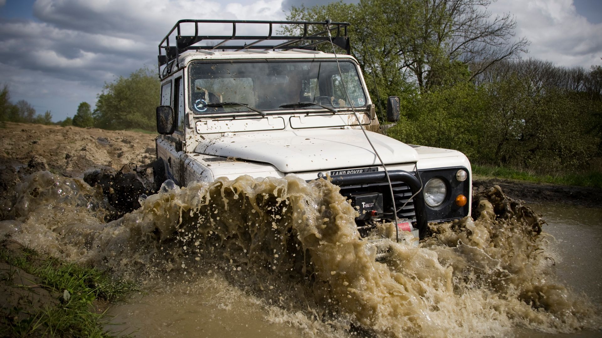 Four-wheel-drive vehicle splashing through deep mud on an off-road trail