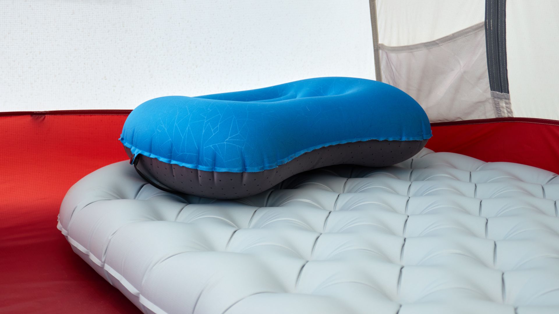 Inflatable camping pillow resting on a sleeping pad inside a tent