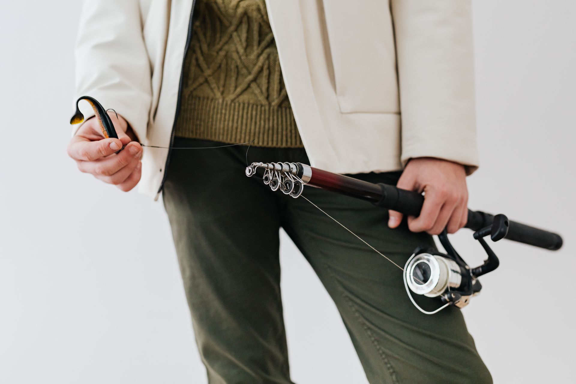 Angler holding a spinning rod with line running out over the water