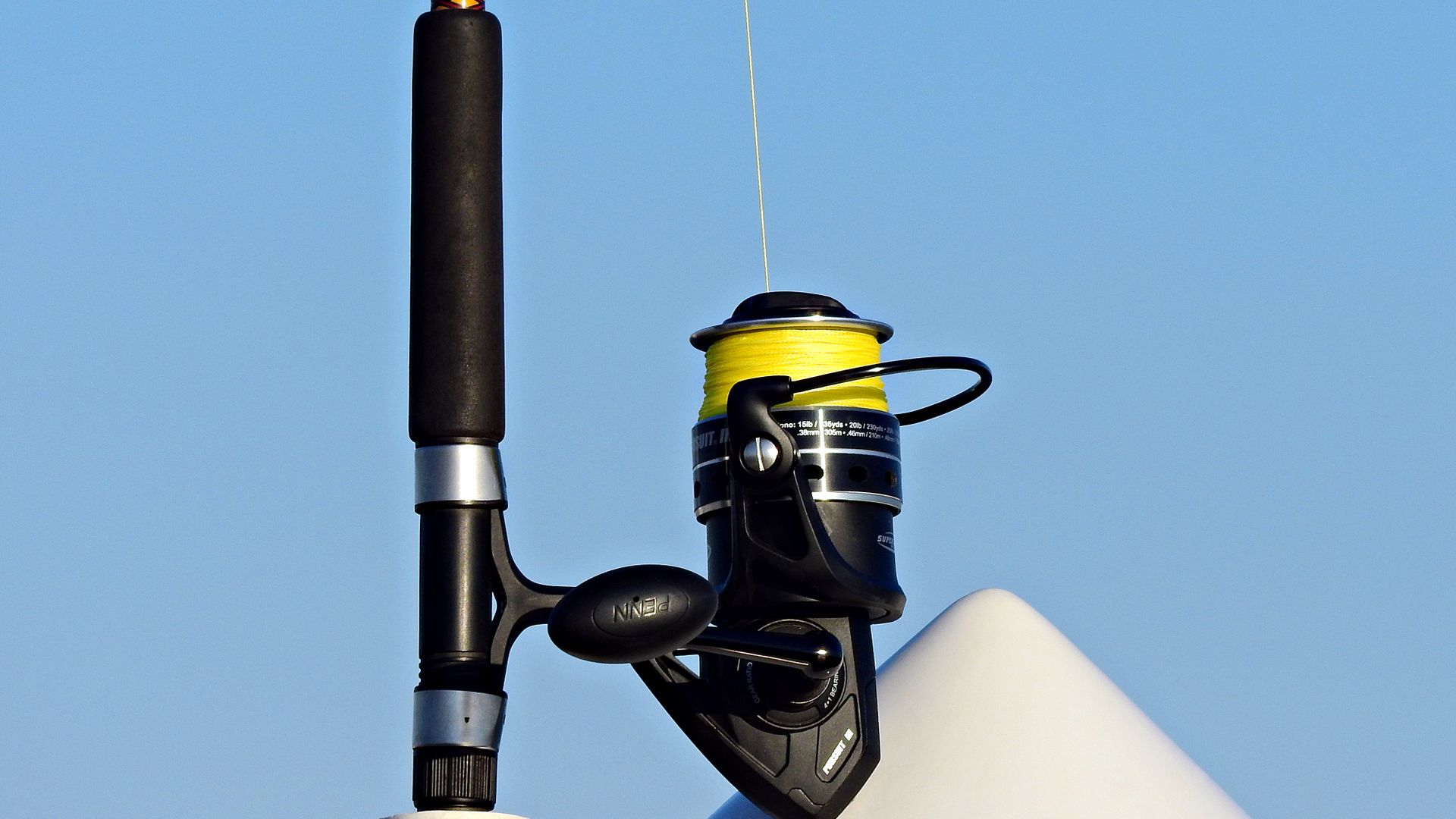 Bright fishing line spooled on a reel against a clear sky