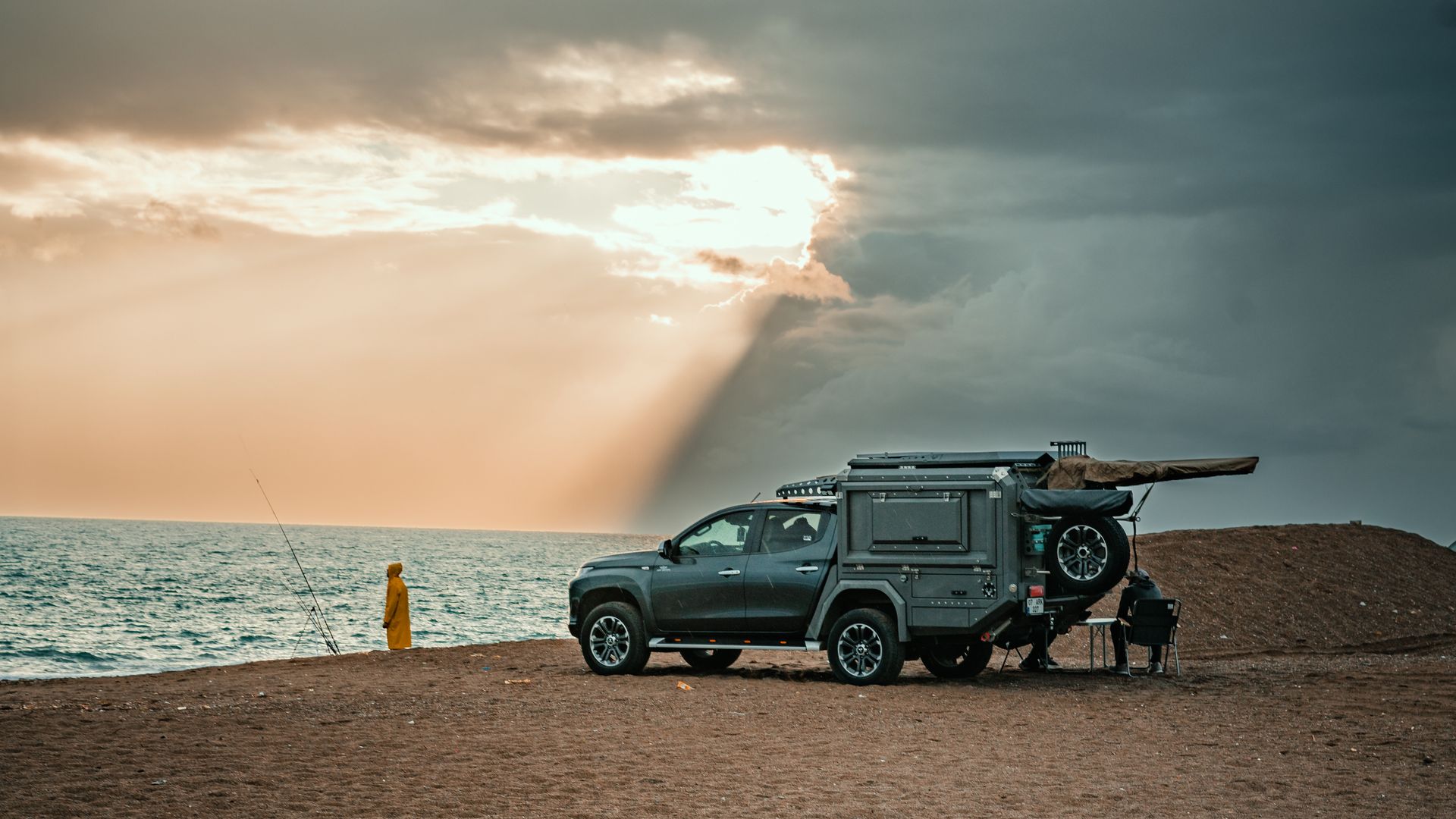 A four-wheel drive loaded with touring gear parked near the coast at sunset