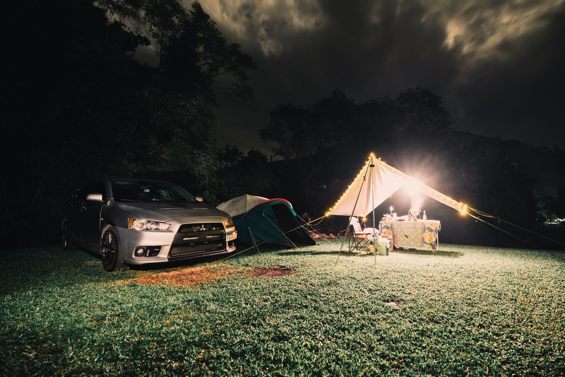 A four wheel drive parked at a grassy campsite lit by bright area lighting at night