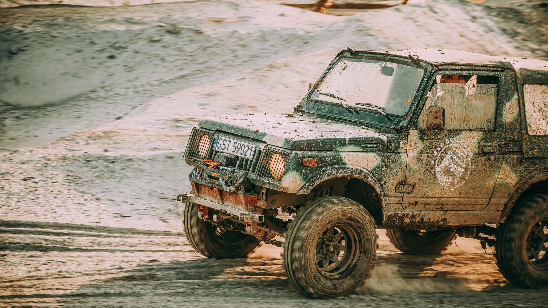 Four-wheel-drive vehicle driving across sandy off-road terrain